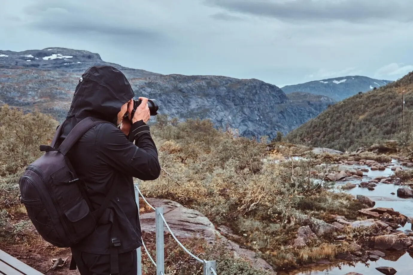 Ein Tourist und Naturfotograf mit Kamera fotografiert im Stehen auf einem norwegischen Berg.